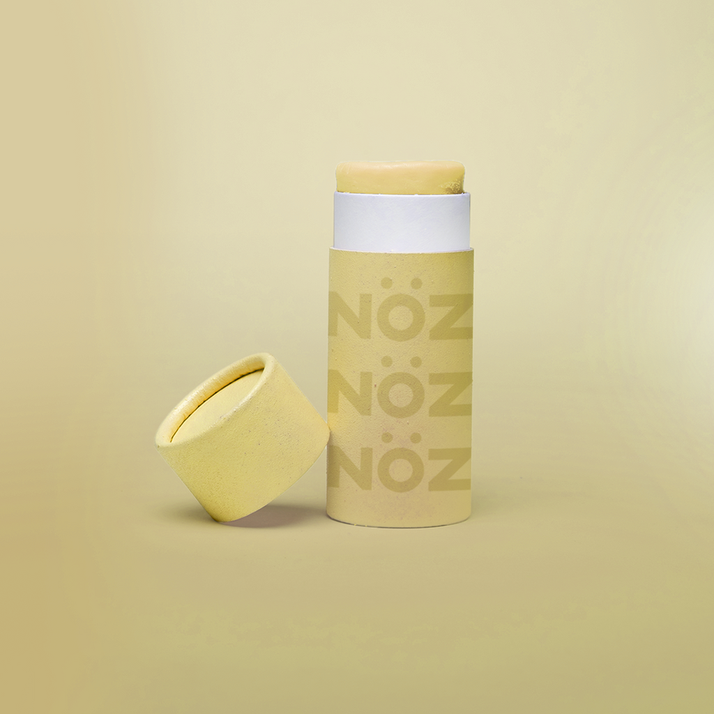 Noz Sunscreen Application Stick in Bright Yellow with cap leaning against it on the left